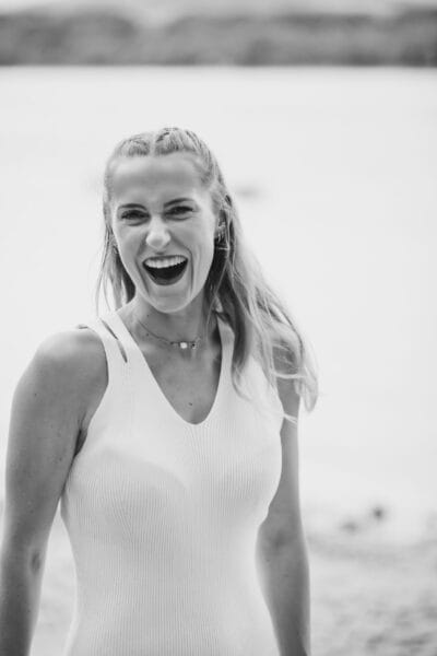risingqueen- Ein Schwarz-Weiß-Foto einer lachenden Frau am Strand, perfekt für Online-Marketingstrategien.